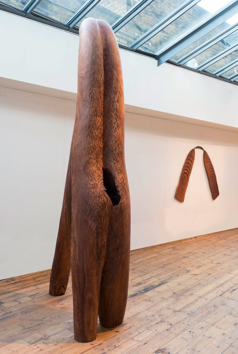 Foreground: BELOVED, 2013, wild tamarind wood, 10'; |  Background: OAR FOR BA (Soul), 2010, mahogany, furniture fragments, 50" x 80"