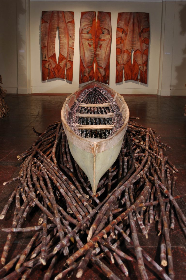 Foreground: THEIR SPIRITS GONE BEFORE THEM, 2006, cottonwood canoe, 16’, 1,357 resin figures, sugar cane. Background: CRUCIFIXION, 2006: triptych, cedar 147” x 78" x 1¼”