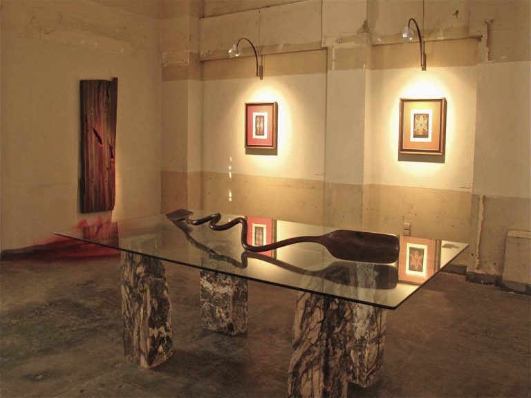 Foreground: PADDLE FOR BOAT OF SOULS, 2010, lignum vitae, 8" x 76" | 
Background: BLOOD OF ZINC, 2006, mahogany and oil, 50" x 100" x 1¼";

