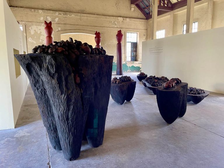 GUIDE THEIR WAY HOME, 2021 Altars of our Heart, Our Children, Our Children’s children, guango, cedar, mahogany, 20’ (x 15’  x7’ | background: THREE GRACES, 2022, guango, 11’ 9”