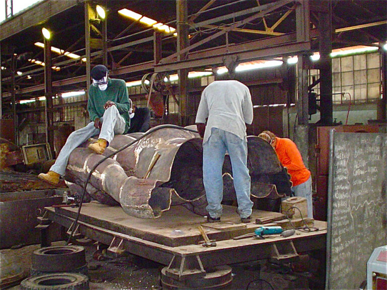 Laura with assistants chasing (putting on texture) female bronze figure in preparation for  patina (finish)