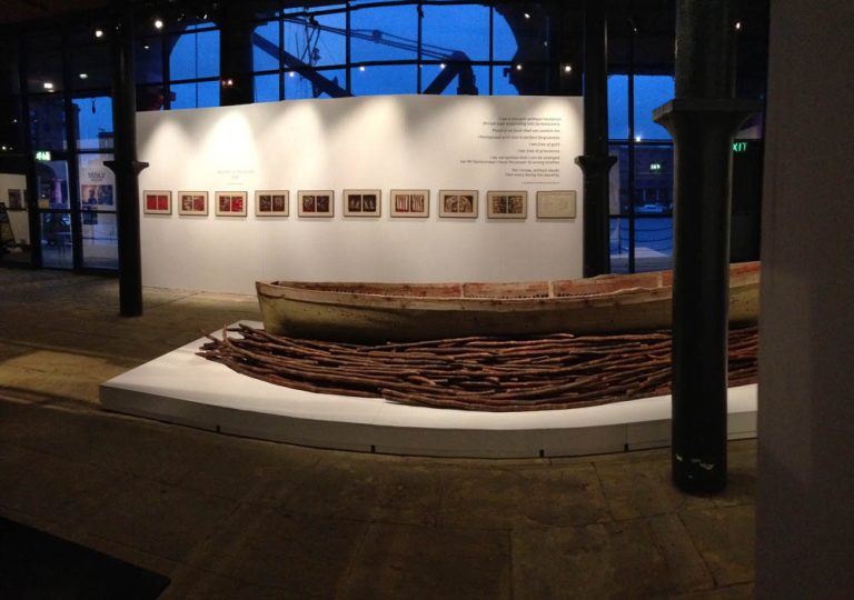 Foreground: part of THEIR SPIRITS GONE BEFORE THEM, 2006, cottonwood canoe, dried sugar cane. Background: WEEPING IN THE BLOOD prints